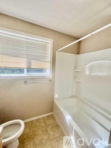 A bathroom with a toilet, a window with blinds, and a shower stall.