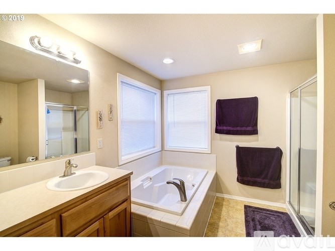 A well-lit, spacious bathroom with a large tub and double sink.