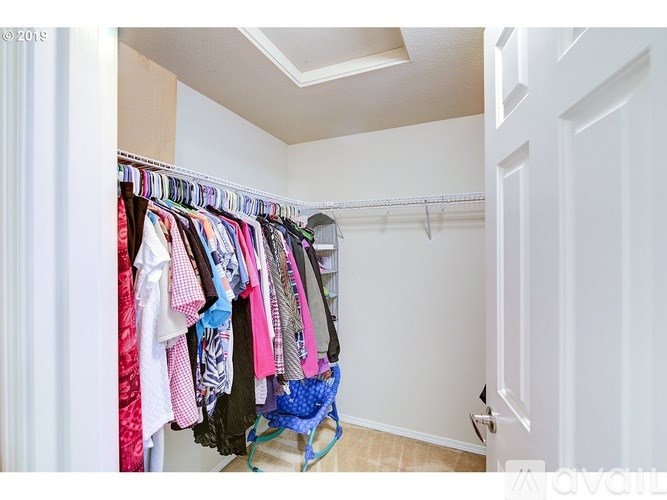 A white closet with clothes hanging on a rail.