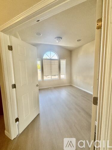 A white door is open to a room with a window.