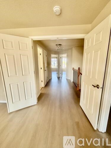 A hallway with white doors and a wooden floor.