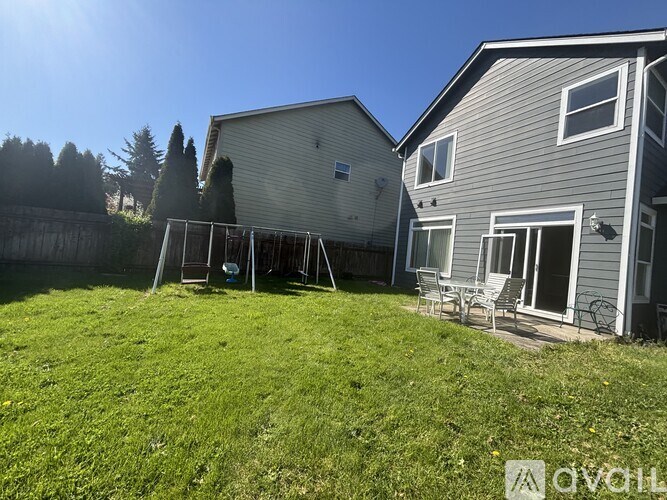 A backyard with a lawn and two houses.