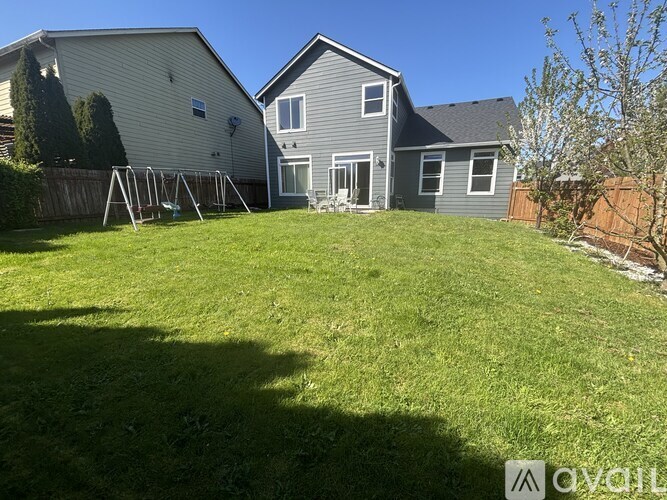 A backyard with a swing set and two houses.
