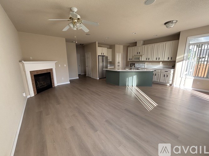 A spacious living room with a fireplace and a kitchen in the background.
