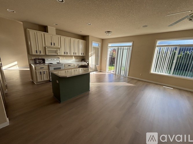 A spacious kitchen with wooden floors and a ceiling fan.
