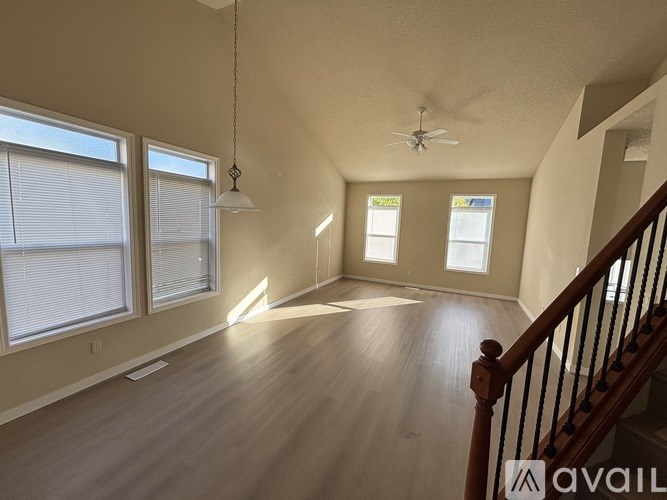 A spacious room with wooden floors and a staircase leading to another room.