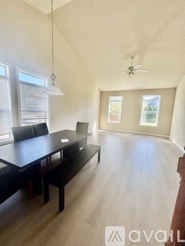 A room with a long table and chairs and a ceiling fan.