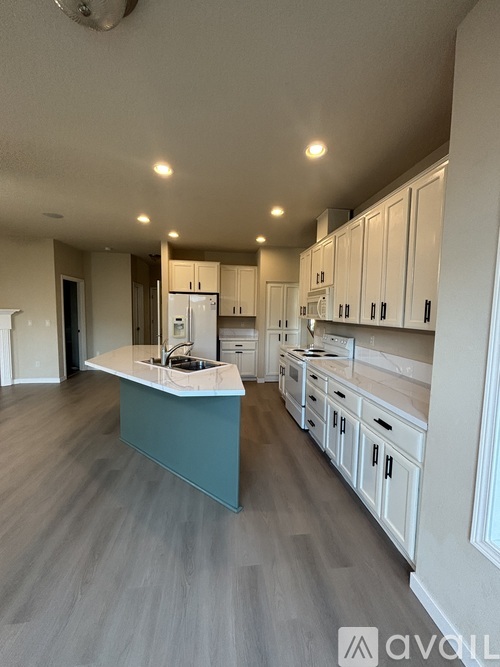 A kitchen with white cabinets and a blue island.
