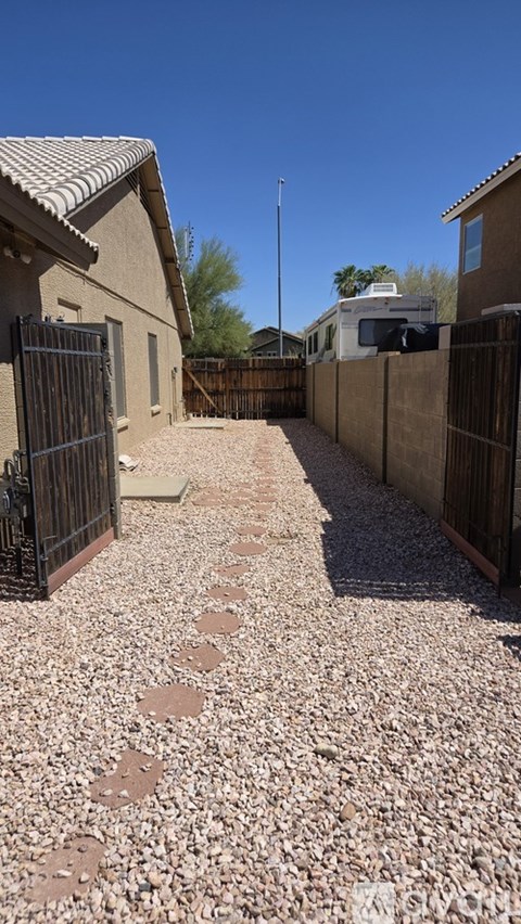 A gravel pathway leads to a house with a black gate.