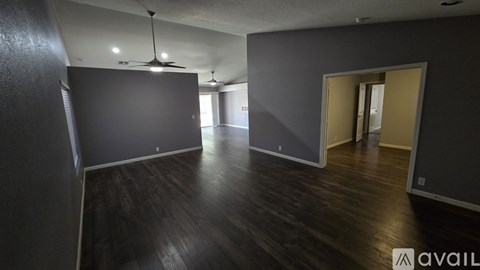 A spacious room with dark wood flooring and a ceiling fan.