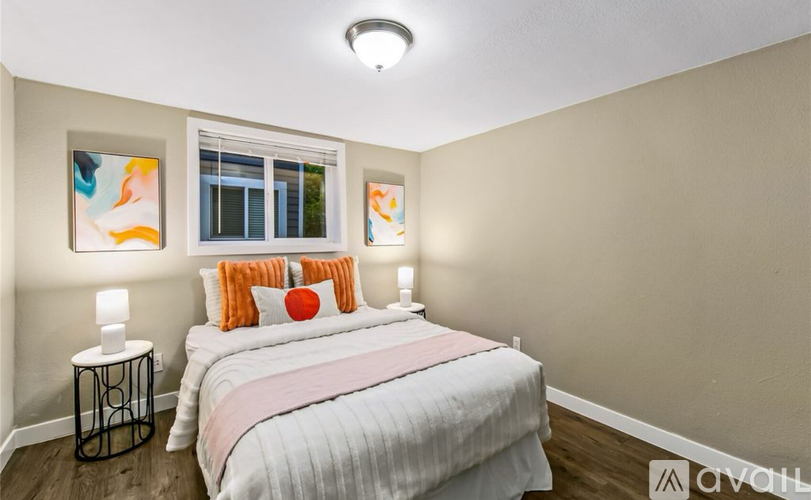 A bedroom with a bed, two lamps, and a window.