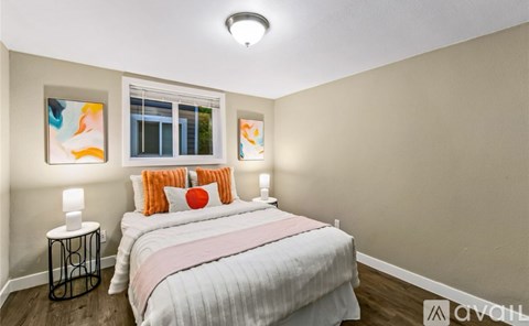 A bedroom with a bed, two lamps, and a window.