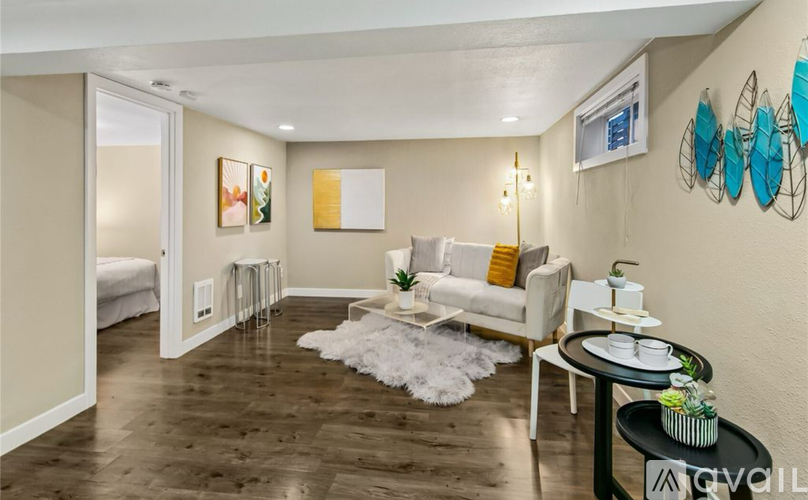 A living room with a white couch, a small table, and a white rug.