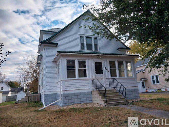 A wooden table with chairs and a vase of flowers in front of a white fridge.