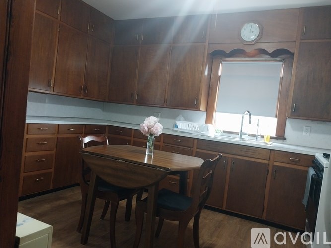 A kitchen with wooden cabinets and a table with chairs.