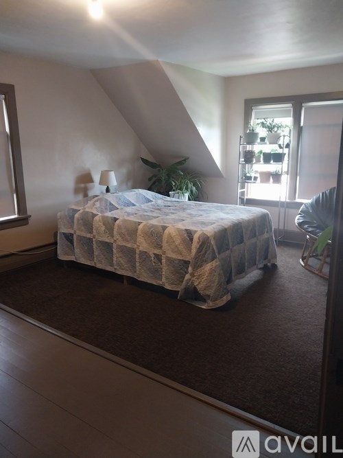 A bedroom with a bed and a chair.