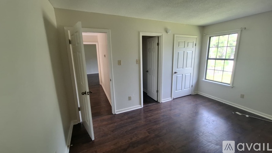 A room with wooden flooring and a window on the left side.