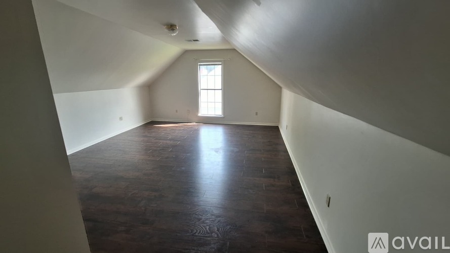 A room with wooden floors and a window overlooking a street.