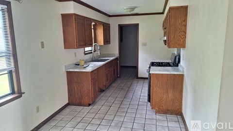 A kitchen with white tiles and wooden cabinets is available for rent.