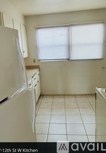 A kitchen with a white refrigerator and white cabinets.