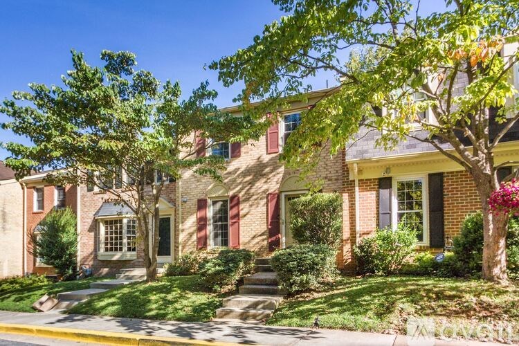 A row of houses with green trees in front.