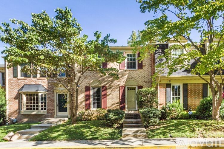 A house with a red door and green shutters is surrounded by trees.