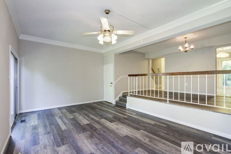 A spacious room with a staircase and a ceiling fan.