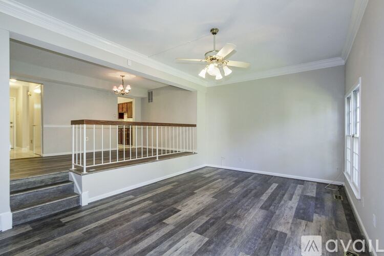 A spacious room with a ceiling fan and a balcony with a railing.