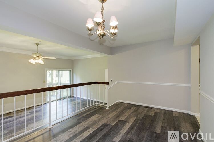 A room with a wooden floor and a balcony with white railings.