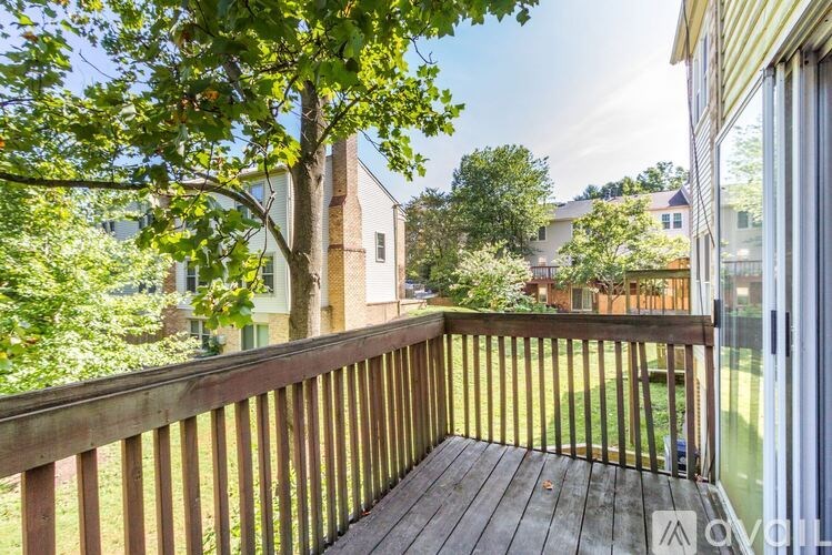A wooden deck with a railing and a tree in the background.