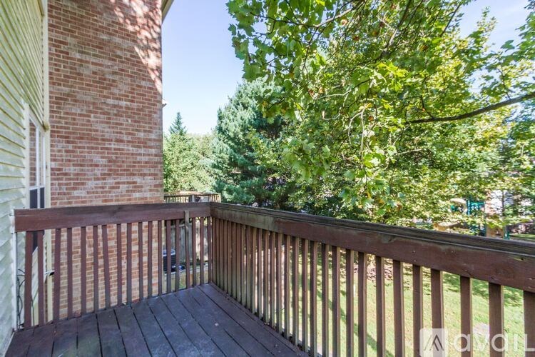 A wooden deck with a railing and a tree in the background.