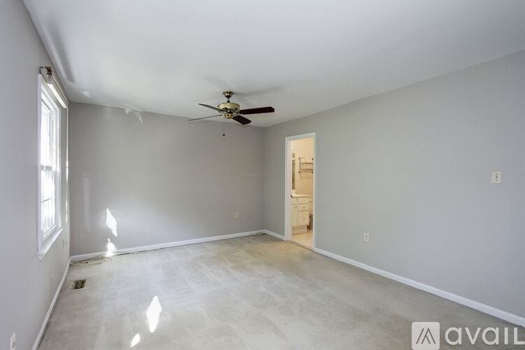 A spacious room with a ceiling fan and a door leading to another room.
