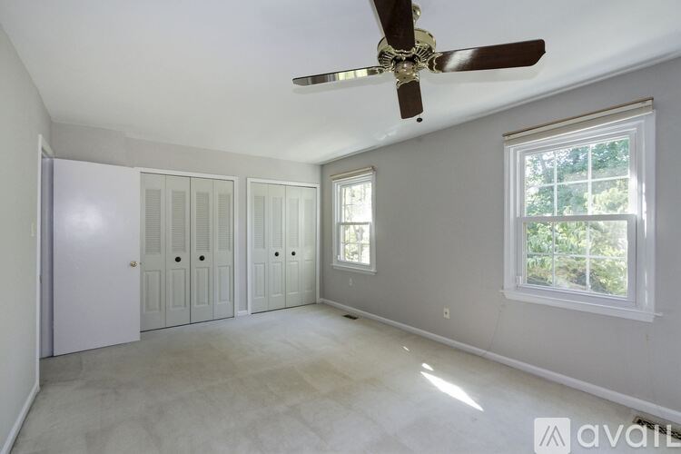 A room with a ceiling fan and a window with a view of trees.