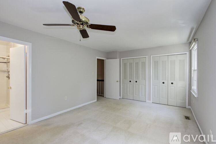 A room with a ceiling fan and white walls.