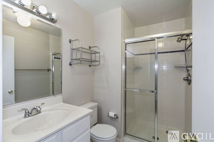 A white bathroom with a sink, toilet, and shower.