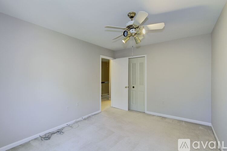 A room with a ceiling fan and a door leading to another room.