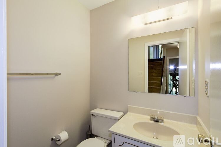 A bathroom with a toilet, sink, and mirror.