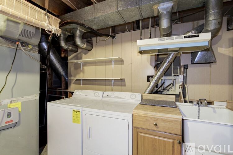A laundry room with a washer and dryer, a sink, and a ventilation system.