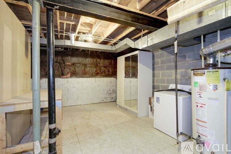 A room under construction with a white refrigerator and a wall of exposed brick.