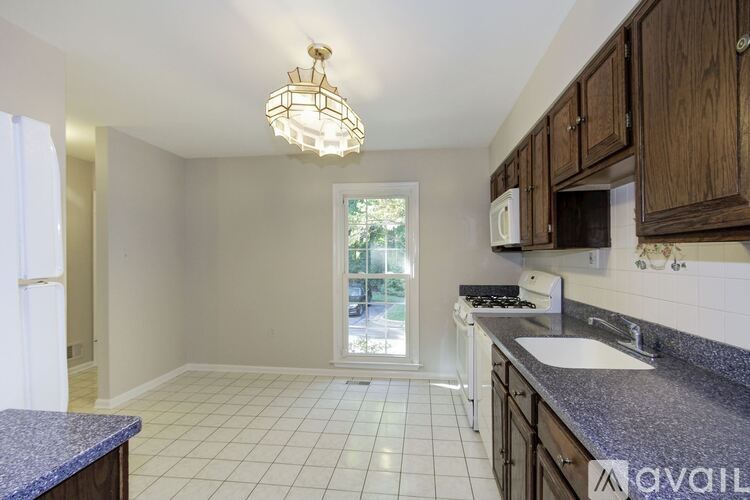 A kitchen with granite countertops and white tiled floors.