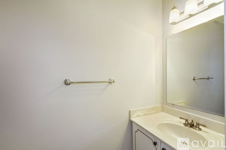 A bathroom with a sink, mirror, and towel rack.