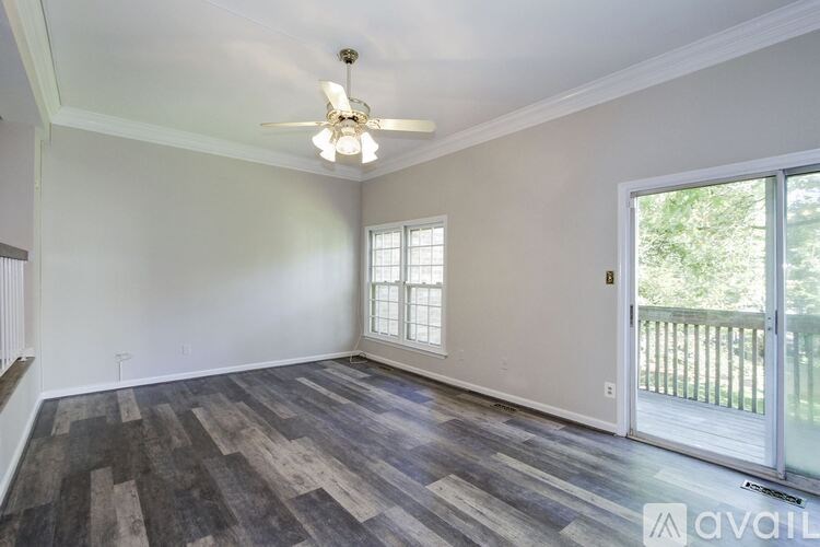 A room with a ceiling fan and sliding glass doors.