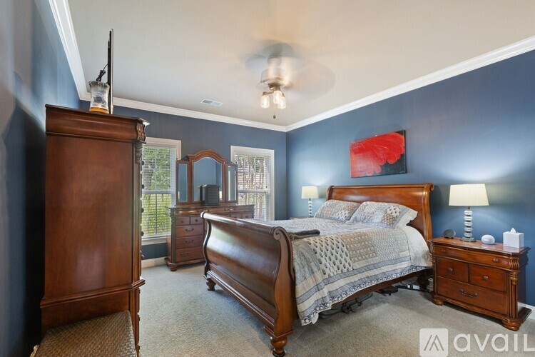 A bedroom with a large bed, a dresser, and a ceiling fan.