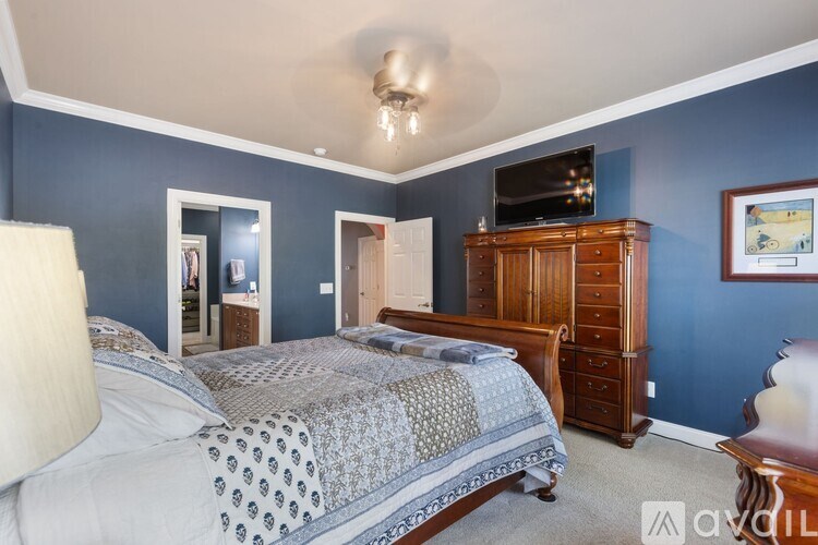 A bedroom with blue walls and a large bed with a patterned comforter.