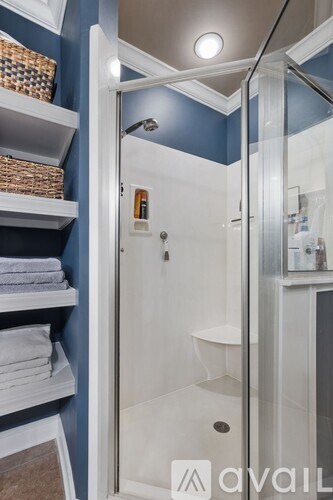 A bathroom with blue walls and a white shower stall.