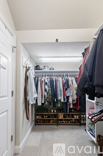 A white closet with clothes hanging and shelves.