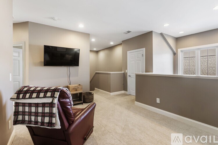 A living room with a brown leather chair and a flat screen TV mounted on the wall.