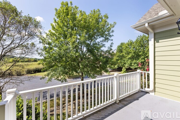 A white railing on a deck with a tree in the background.