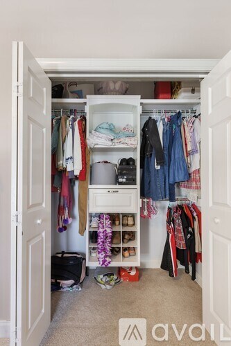 A white closet with clothes and shoes.