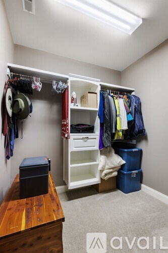 A small closet with a wooden bench and a black container on top.